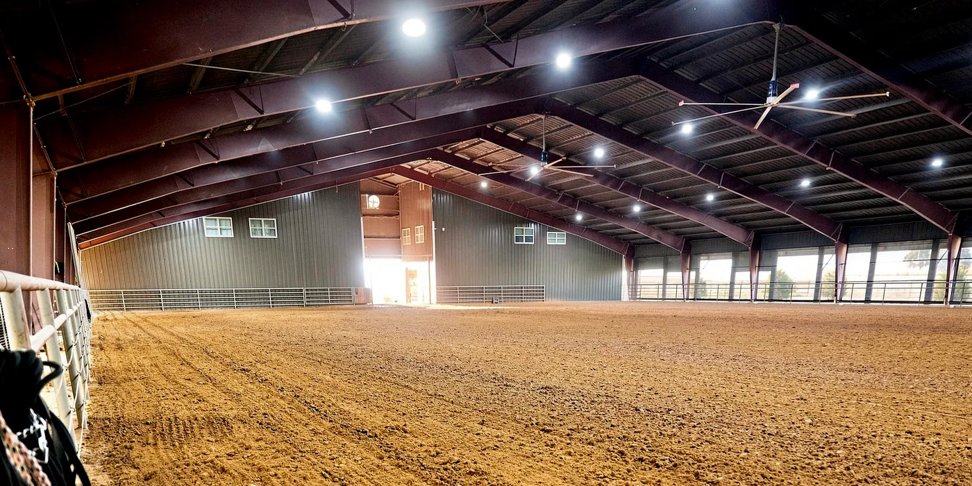 The covered arena, with sand footing, overhead fans, and open sides along one wall.