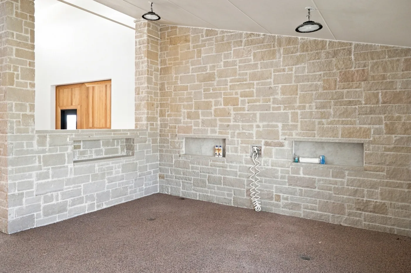 A stone wash stall, with recessed shelving and a coiled hose.